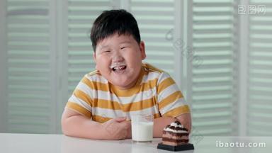 快乐的小胖男孩喝牛奶吃蛋糕